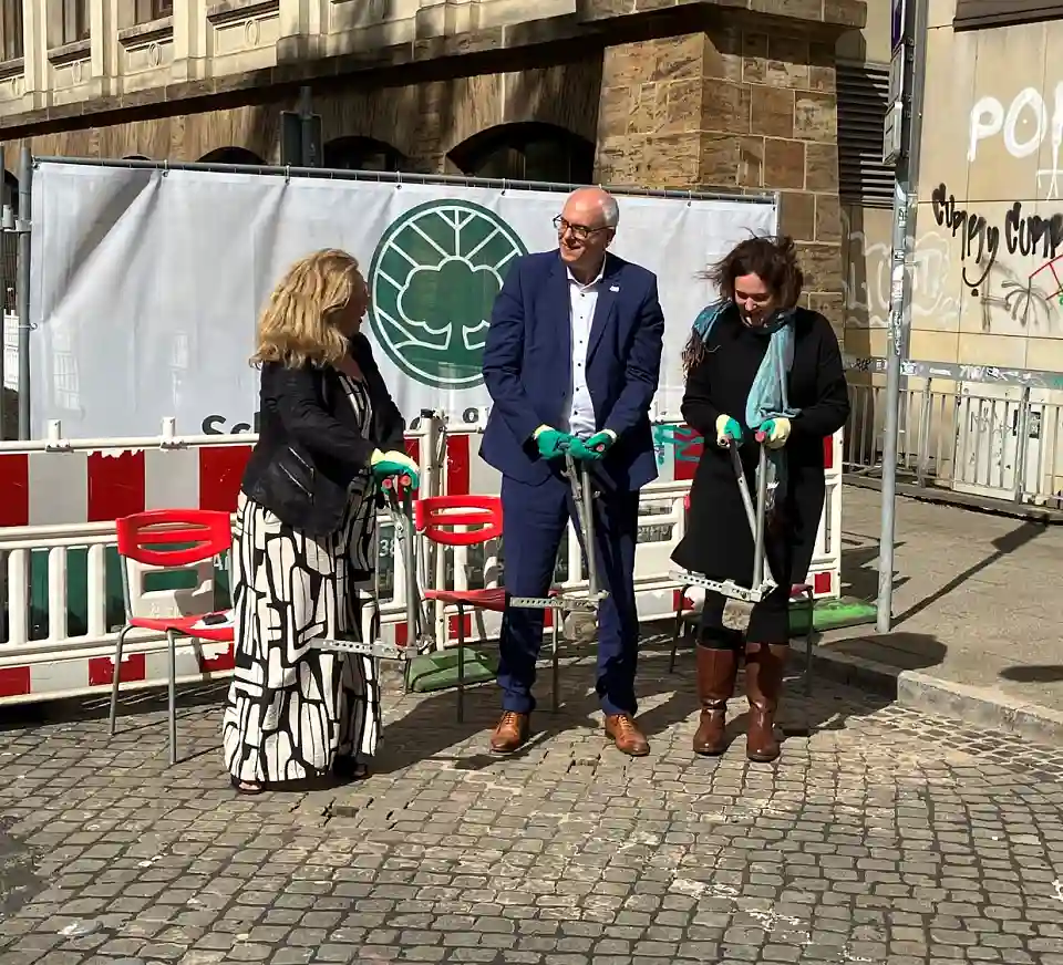 Von links nach rechts: Senatorin Ünsal, Bürgermeister Bovenschulte und Senatorin Moosdorf nehmen Steine aus dem Pflaster auf.