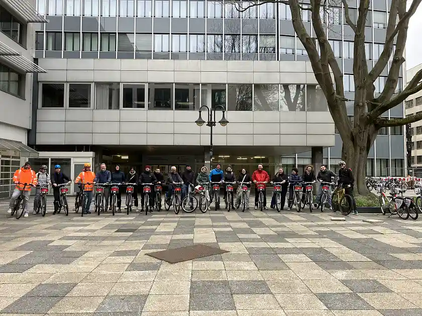 Gruppenbild vor dem SBMS-Gebäude - zu sehen sind Personen mit Fahrrädern im Halbkreis.