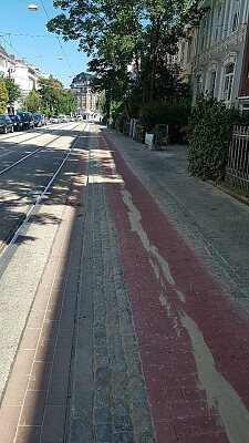 Der frisch sanierte Radweg Am Dobben aus roten Steinen. Links davon Straßenbahnschienen, rechts der Gehweg und Häuser