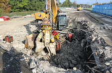 Bild vom Brückenrückbau, ein Baustellenfahrzeug in einer Grube, ringsherum Material der Brücke