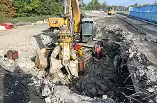Bild vom Brückenrückbau, ein Baustellenfahrzeug in einer Grube, ringsherum Material der Brücke
