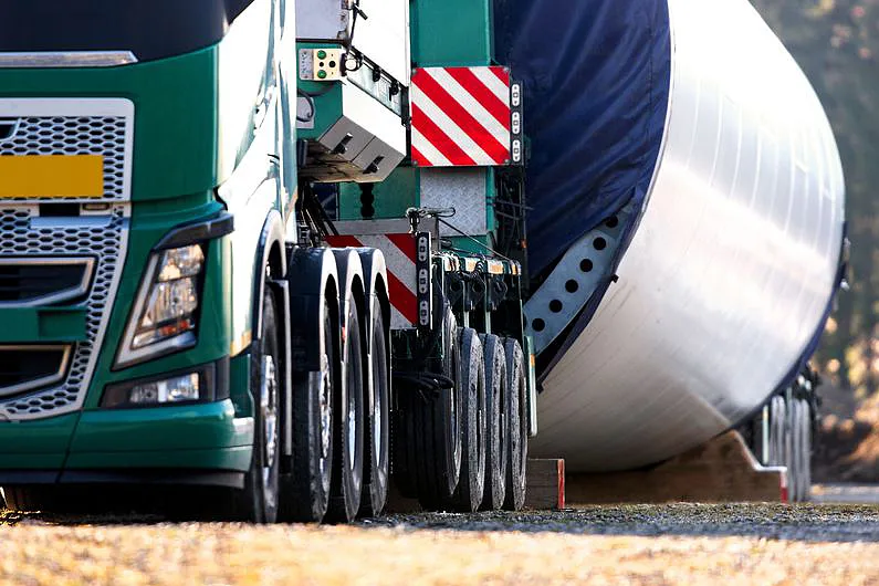 Ausschnitt eines schweren grünen LKW mit einem Windradteil, Bild: photocase/Tekka77