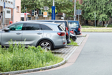 Parkende Autos auf einer Parkfläche in der Innenstadt. Es ist rechts ein Teil einer Straße und Begrünung im Vorder- und Hintergrund des Bildes sichtbar. Bild: ASV