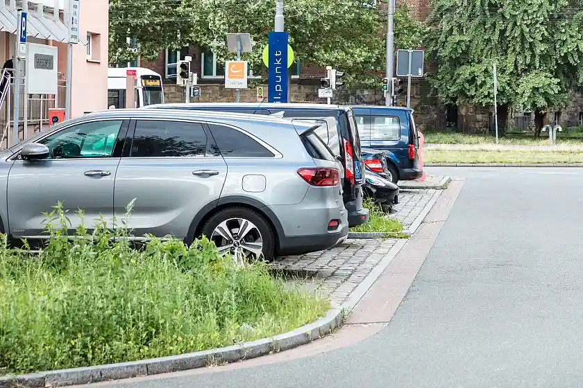 Parkende Autos auf einer Parkfläche in der Innenstadt. Es ist rechts ein Teil einer Straße und Begrünung im Vorder- und Hintergrund des Bildes sichtbar. Bild: ASV