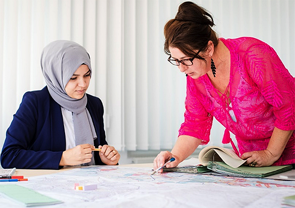 Zwei Frauen an einem Tisch, die einen Plan  besprechen