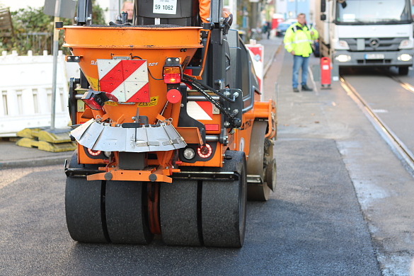 Eine Walze verdichtet heißen Asphalt