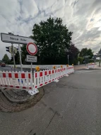 Zu sehen sind Straßenbauarbeiten. Die Fahrbahndecke wird unter Absperrungen erneuert.