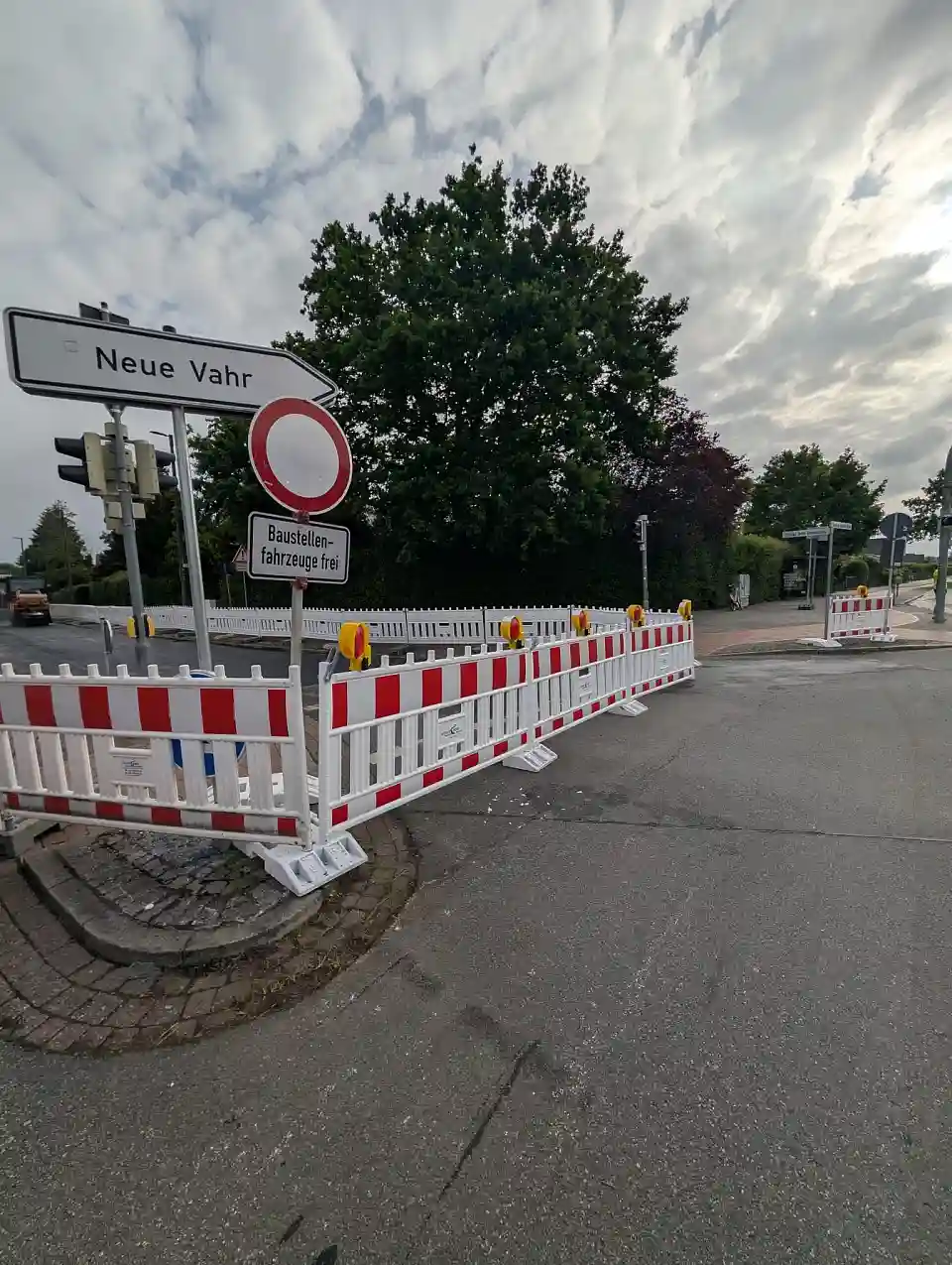 Zu sehen sind Stra&szlig;enbauarbeiten. Die Fahrbahndecke wird unter Absperrungen erneuert.