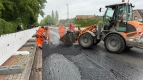 Zu sehen sind Straßenbauarbeiten. Die Fahrbahndecke wird unter Absperrungen erneuert.