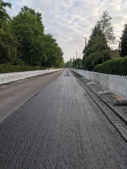 Zu sehen sind Straßenbauarbeiten. Die Fahrbahndecke wird unter Absperrungen erneuert.