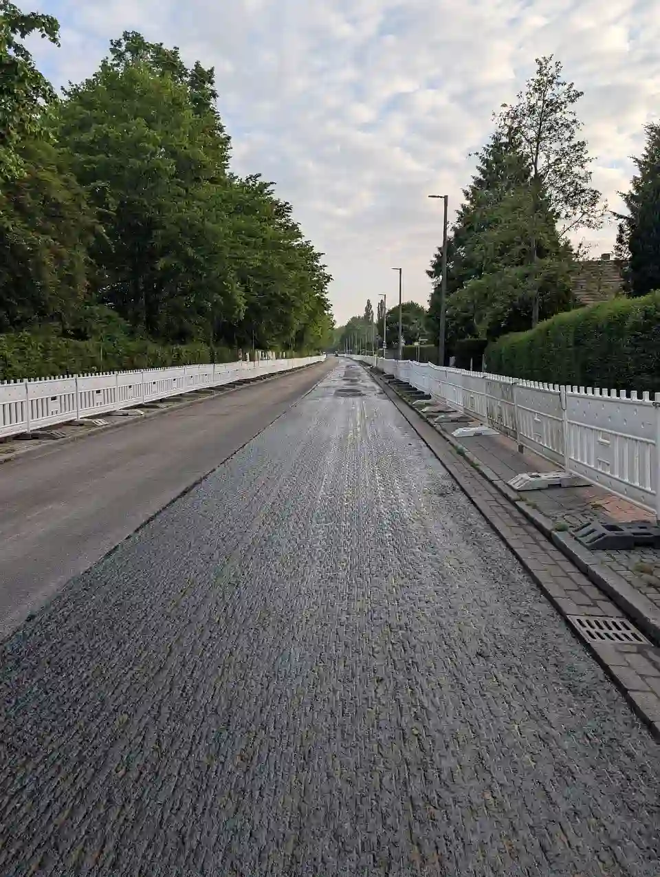 Zu sehen sind Stra&szlig;enbauarbeiten. Die Fahrbahndecke wird unter Absperrungen erneuert.
