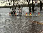 Überflutete Borgfelder Landstraße mit Absperrgittern und Bäumen, die von Wasser umspült werden.  Dezember 2023, Bild: ASV