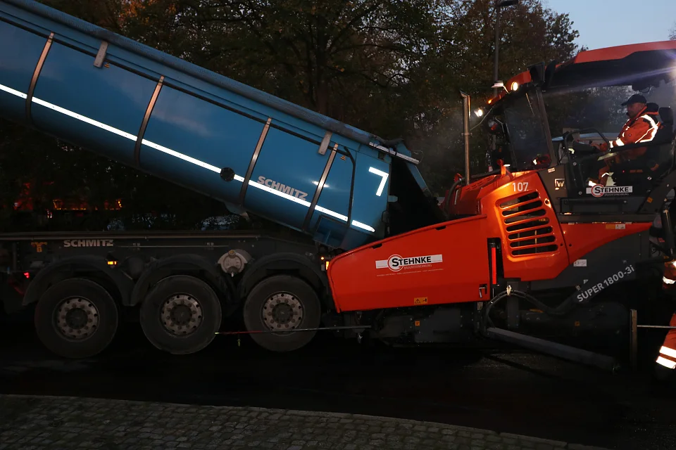 Um circa 07:30 Uhr wird der erste Lkw am Fertiger angedockt und kippt den Asphalt dort hinein.