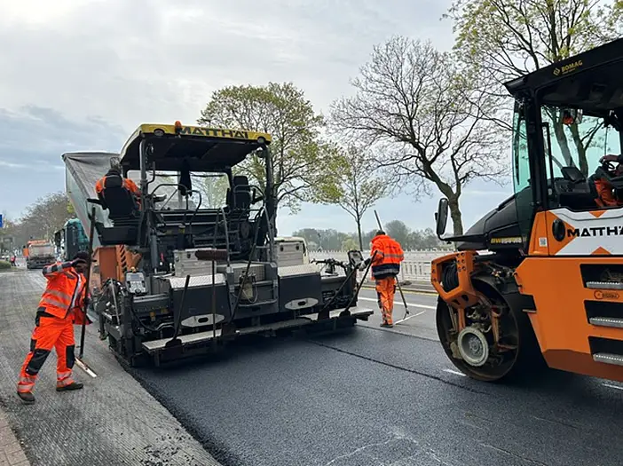 Hei&szlig;er Asphalt wird auf einem Teilst&uuml;ck des Osterdeichs aufgebracht.
