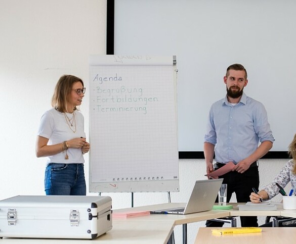 4 Personen vor einer Tafel im Gespräch mit blick Richtung Kamera