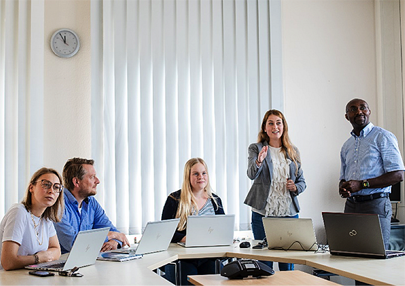 Gruppe im Planungsgespräch mit Labtops am Tisch.