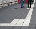 Menschen an einer Haltestelle mit Blindenleitsystem